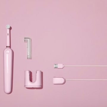 Pink electric toothbrush with charging base and cable